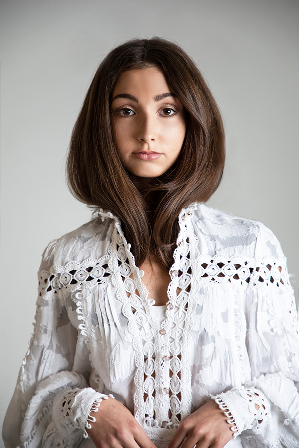 A studio portrait built on one clean light and a lace blouse against a grey seamless.
